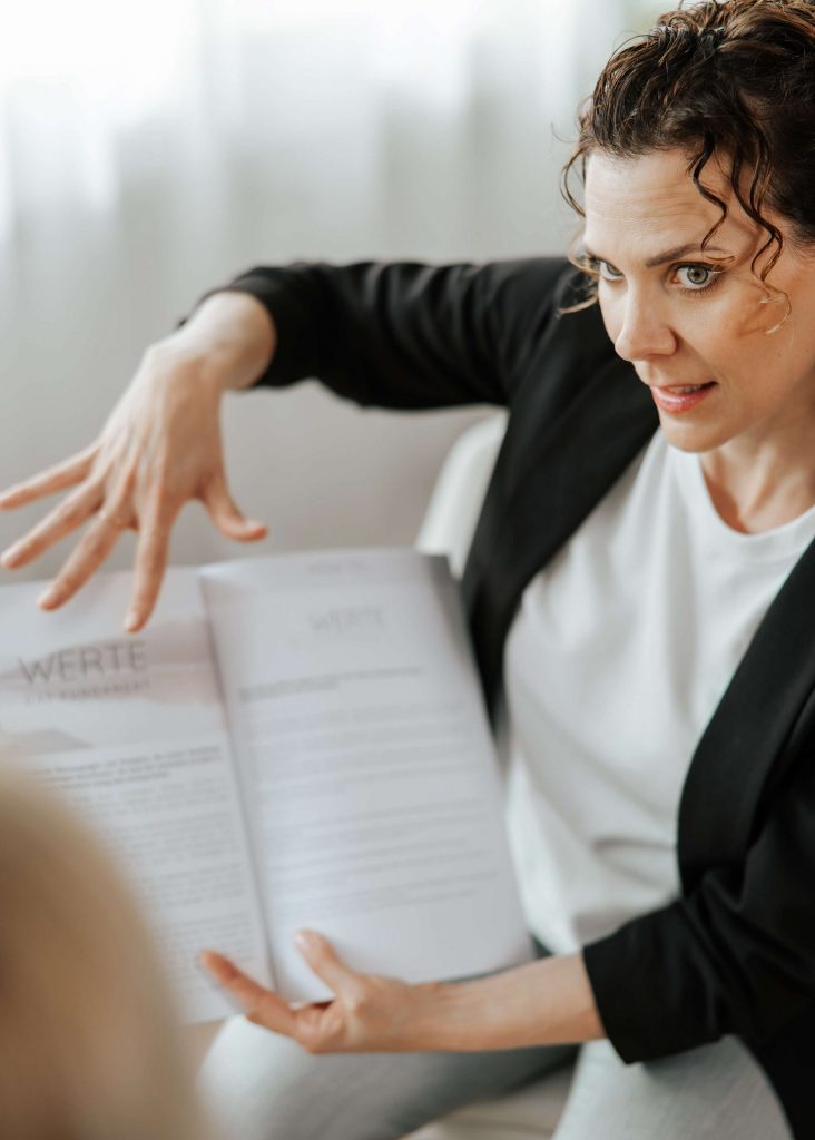 Andrea Görlich erläutert ein Kapitel über Werte aus ihrem Workbook, emotionale und ausdrucksstarke Geste während des Coachings.